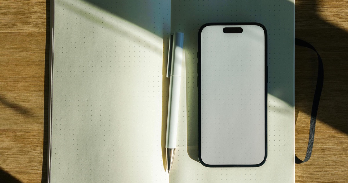 Notebook, pen, and phone prepared for journal-based Spanish speaking practice